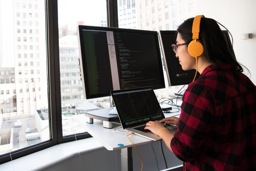 girl programming with 3 computer monitors