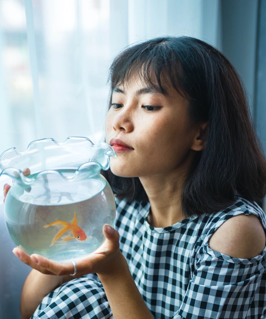 woman looking at a goldfish